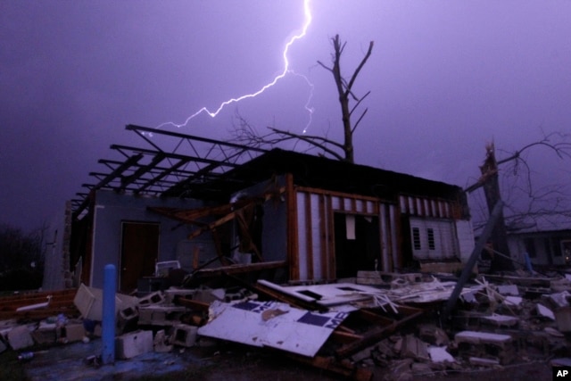 FILE - Lightning illuminates a house after a tornado touched down in Jefferson County, Ala., damaging several houses in Birmingham, Dec. 25, 2015.