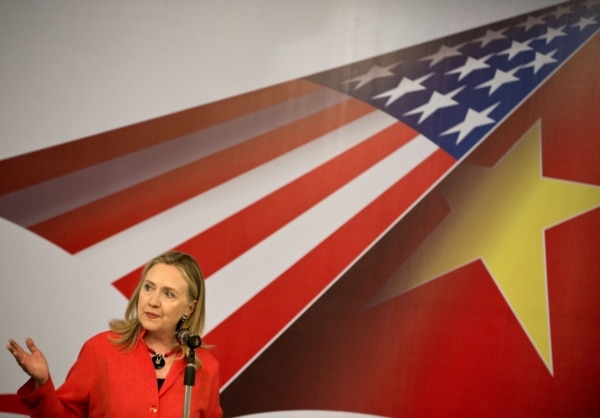 U.S. Secretary of State Hillary Clinton speaks in front of U.S. flag and Vietnamese flag.