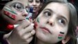In this citizen journalism image provided by Aleppo Media Center AMC which has been authenticated based on its contents and other AP reporting, Syrian girls paint their faces with colors of the Syrian revolutionary flag during a fesitval, in Aleppo, Syria.