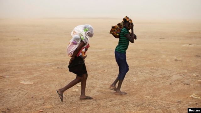 Women wrapped in shawls walk through a sandstorm in Timbuktu, July 29, 2013.