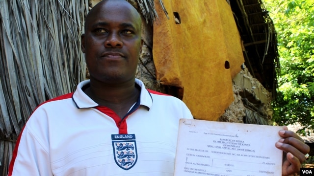 Felix Karisa hold up the notice ordering the eviction of his entire village outside Mombasa, Kenya, November 18, 2012. (H. Heuler/VOA)
