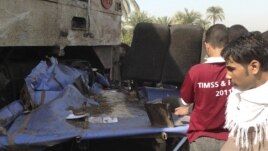 Relatives of victims look at the wreckage of a bus after a train (L), with bloodstains, crashed into it at Manflot in the southern city of Assuit, 500 km (310 miles) south of Cairo, November 17, 2012. Forty-nine people, mostly children, were killed when t