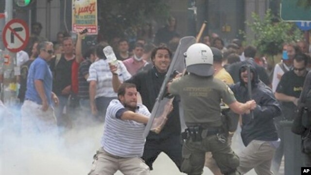 Greek protester uses a baton to hit a riot police officer during clashes in Athens' main Syntagma square, June 15, 2011