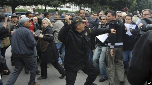 A police officer faces protesters during a demonstration against the Constitutional Democratic Rally - RCD, the party of deposed President Ben Ali, in the center of Tunis, 18 Jan 2011
