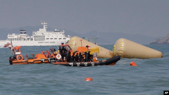 South Korean rescue team members on a boat approach to the buoys which were installed to mark the area of the sunken ferry Sewol in the water off the southern coast near Jindo, south of Seoul, South Korea, Sunday, April 20, 2014.