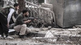 Syrian rebel fighters take cover as a Syrian army sniper aims over a destroyed mosque in Tarik Al-Bab, southeast of Aleppo, October 26, 2012.