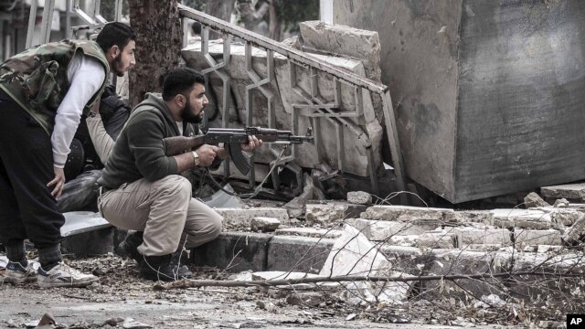 Syrian rebel fighters take cover as a Syrian army sniper aims over a destroyed mosque in Tarik Al-Bab, southeast of Aleppo, October 26, 2012.