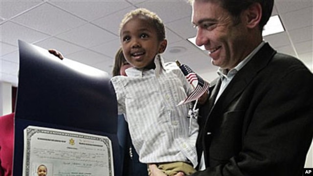 Aaron Lieberman holds his son Theodore, 2, adopted from Ethiopia, as he shows his citizenship certificate, during U.S. Citizenship and Immigration Services (USCIS) Adoption Day ceremony in New York, 18 Nov 2010