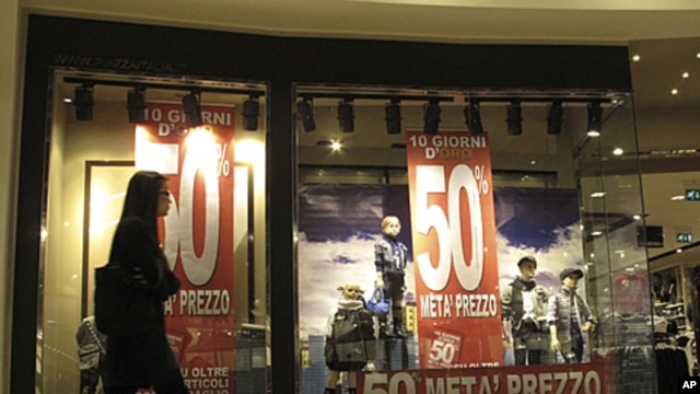 A woman walks past the window of a clothes store announcing 50 percent discounts in downtown Milan, Italy, November 7, 2011.