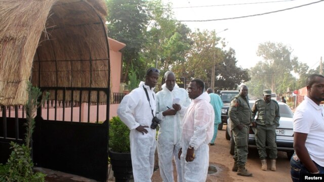 FILE - Health officials stand outside La Terrasse restaurant in Bamako, where five people were killed in a militant attack, March 7, 2015.