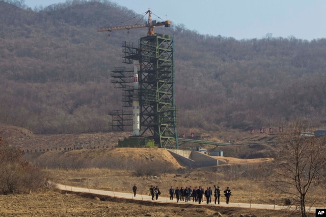 FILE - A group of journalists walk down a road in front of North Korea's Unha-3 rocket at the Sohae Satellite Station in Tongchang-ri, North Korea.