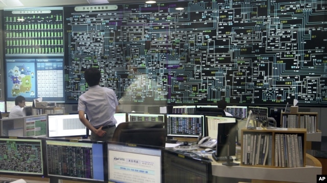 کارمند یک شرکت دولتی در حال نظارت به مانیوتر بزرگی است که عرضه برق را نشان می دهد  