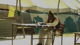Organizers, using pen and pad, record missing persons names to be broadcasted on megaphone