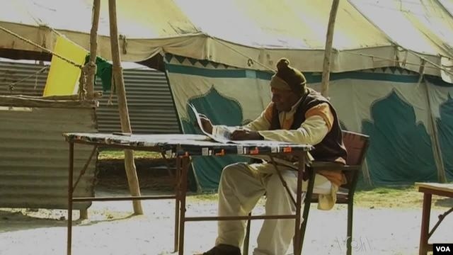 Organizers, using pen and pad, record missing persons names to be broadcasted on megaphone