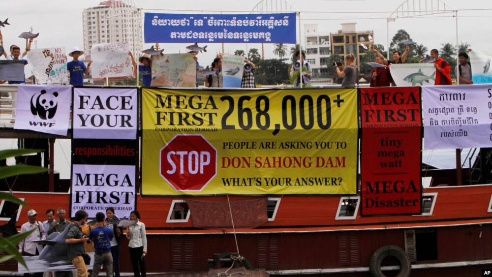 FILE - Cambodian non-governmental organization (NGOs) activists shout slogans during a protest against a proposed Don Sahong dam, in a tourist boat along the Tonle Sap river, in Phnom Penh, Cambodia, Thursday, Sept. 11, 2014.