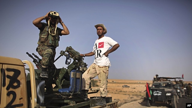A former rebel fighter looks through binoculars as he stands in a convoy of revolutionary forces, moments before heading to the frontline in Bani Walid, at a checkpoint in Wadi Dinar, Libya,  September 16, 2011.