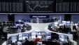 Traders work at their desks in front of the German share price index, DAX board, at the stock exchange in Frankfurt, Germany, April 12, 2016.  