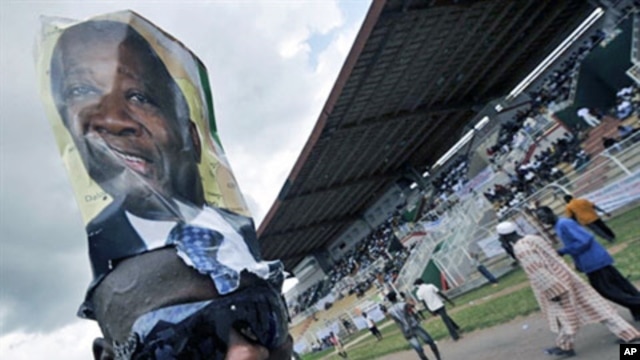 A supporter wears a poster on his head of Ivory Coast Laurent Gbagbo during a rally at a stadium in Bouake ahead of the 31 Oct 2010 elections (File)