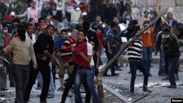Anti-Morsi protesters throw stones towards riot police during clashes in Simon Bolivar Square, which leads to Tahrir Square, in Cairo, Egypt, January 30, 2013.