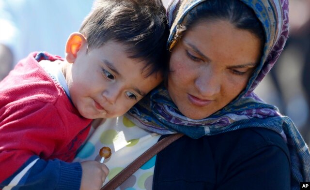 A Syrian woman carries a child as she arrives near the Hungarian border with Serbia, in Roszke, southern Hungary, Sept. 9, 2015.