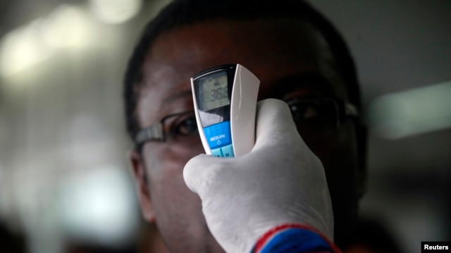 A health worker takes a passenger's temperature with an infrared digital laser thermometer at the Felix Houphouet Boigny international airport in Abidjan, Ivory Coast, Aug. 13, 2014. 