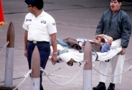 Trung sĩ Không quân James Cook, bị thương nặng sau khi máy bay của ông bị bắn hạ ở bầu trời miền Bắc Việt Nam tháng 12 năm 1972, vung tay chào kính lá cờ Mỹ từ chiếc cáng của mình trong lúc được khiêng lên máy bay (US Air Force photo)