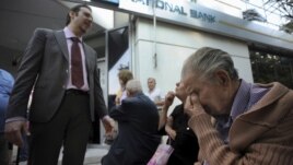 Một giám đốc ngân hàng giải thích tình hình cho những người về hưu chờ đợi bên ngoài một chi nhánh của Ngân hàng Quốc gia Hy Lạp ở Thessaloniki để nhận lương hưu, ngày 29/6/2015.