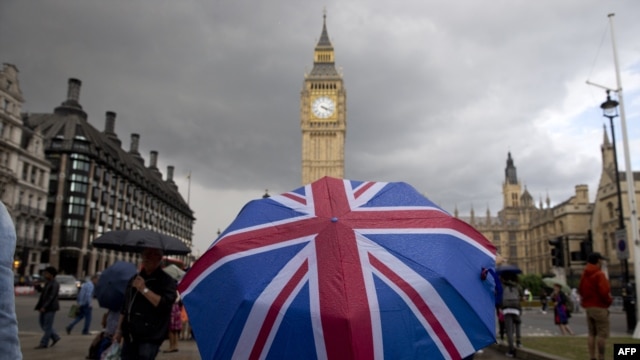 FILE - A pedestrian shelters from the rain beneath a Union Jack-themed umbrella near the Big Ben clock face and the Elizabeth Tower at the Houses of Parliament in central London, following the pro-Brexit result of the UK's EU referendum vote, June 25, 2016.