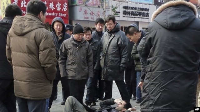 Unidentified men surround a foreign journalist who was pushed to the ground on Wangfujing Street after calls for a anti-government rally in  Beijing, Feb. 27, 2011