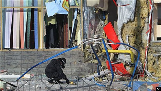 An investigator works at the scene of one of two explosions near the city's market in the eastern Ukrainian town of Makiyivka, 20 Jan 2011