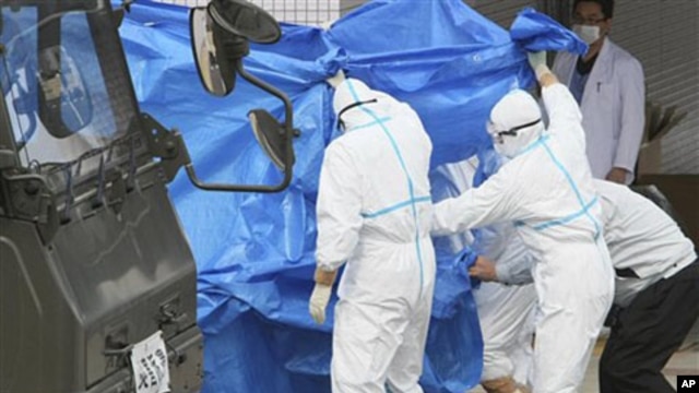 Japan's Self-Defense Force's members and others in protective gear help to transfer workers who stepped into contaminated water on Thursday during their operation at the Fukushima Daiichi nuclear plant, March 25, 2011