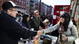 Felice Vazquez greets a neighbor as she mans a table providing hot drinks and snacks on Washington Street as the buildings around them remain without power due to damage caused by Superstorm Sandy in Hoboken, New Jersey, November 4, 2012.