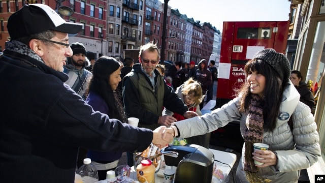 Felice Vazquez greets a neighbor as she mans a table providing hot drinks and snacks on Washington Street as the buildings around them remain without power due to damage caused by Superstorm Sandy in Hoboken, New Jersey, November 4, 2012.