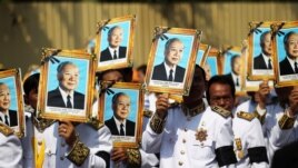 Procession participants shield themselves from the sun with portraits of the late former Cambodian King Norodom Sihanouk in a funeral procession in Phnom Penh, February 1, 2013.