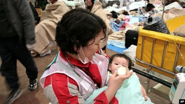 Japanese Red Cross Society worker feeds baby at relief center