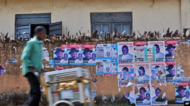 A Nigerian man hawks snacks along a street lined with destroyed posters advertising Presidential candidate Jonathan Goodluck at Jos, Apr 15 2011