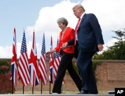 El presidente Donald Trump y la primera ministra británica Theresa May se toman de la mano al concluir una conferencia de prensa conjunta en Chequers, Buckinghamshire, Inglaterra, el 13 de julio de 2018.