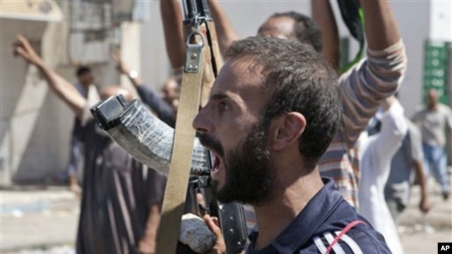 In this Sunday, Aug. 14, 2011 photo, a Libyan rebel fighter in Zawiya, western Libya, reacts to the news that the city of Surman, an important strategic point, is now under the control of the rebel forces.