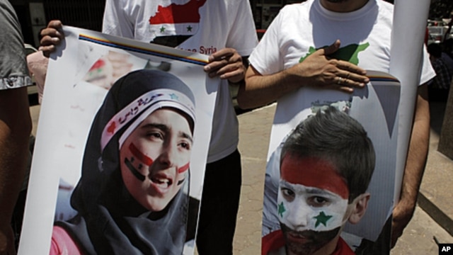 Two protesters carry posters with pictures of unidentified relatives in Syria,  with the Syrian flag colors painted on their faces during an anti-Syrian regime rally near the Syrian embassy in Cairo, Egypt,  July 5, 2011