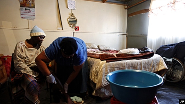 AIDS patient Anna Bosigo (L) has her leg massaged by volunteer worker Lydia Mbhalo, of the Sakhi-Sizwe AIDS care initiative, in the Orange Farm township, south of Johannesburg, August 23, 2011.