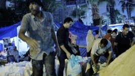 At the edge of the pro-Morsi camp, men shovel sand in bags to pile around their tent city, July 29, 2013. Protesters say they believe sand will stop bullets better than the brick walls they erected over the weekend. [Hamada Elrasam/VOA)