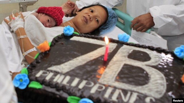 United Nations Population Fund staff gives a cake to the family of newborn baby girl named Danica Camacho, the Philippines' symbolic 'seven billionth baby' who is part of the UN's seven billion global population projection, in Fabella Maternity hospital i