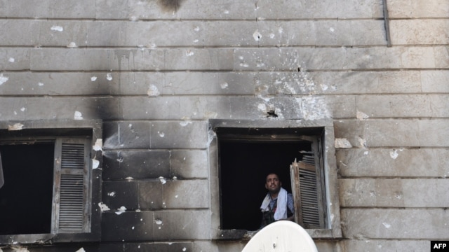 Free Syrian Army fighter looks out from the window of the burnt Shaar district police station in the northern Syrian city of Aleppo after it was overrun by rebel fighters on July 25, 2012. 