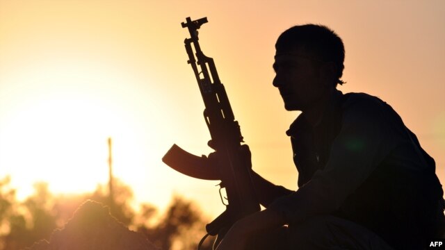 Một chiến binh người Kurd tạo dáng lúc mặt trời mọc tại thành phố Ain Issi của Syria, cách Raqqa khoảng 50 km về phía bắc.