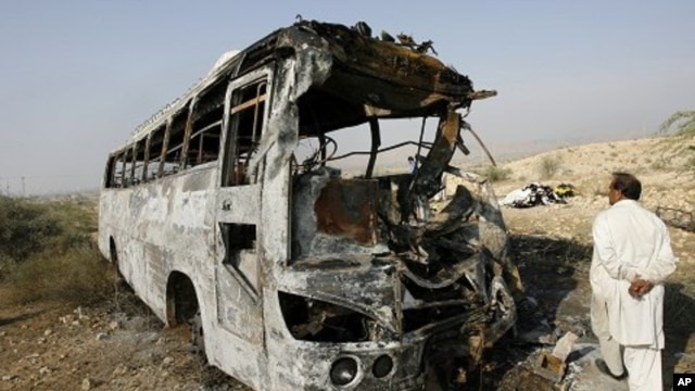 A man walks past the wreckage of a bus which was burned after it collided with an oil tanker in Nooriabad, in Pakistan's Sindh province 23 Jan 2011.