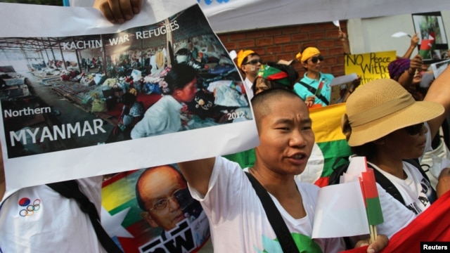 A minority Kachin holds up an image showing Kachin refugees in northern Burma during a protest in front of Burmese Embassy in Bangkok, Thailand, January 11, 2013. 