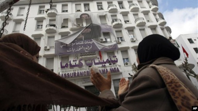Women applause as they look at a torn banner depicting former Tunisian President Zine El Abidine Ben Ali in the center of Tunis, Sunday, Jan. 16. 2011.