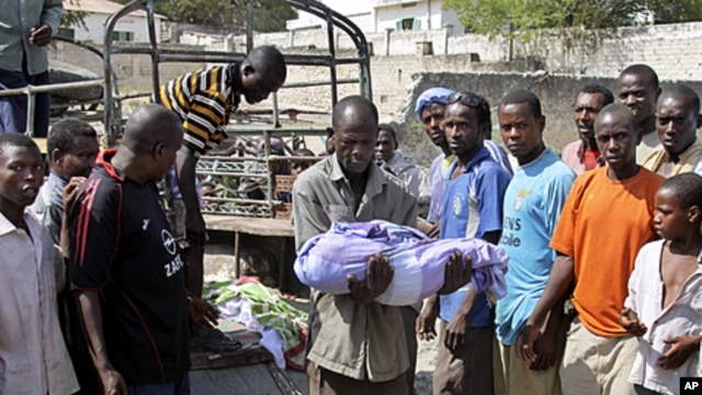 A Somali man carries the body of a one year old child who was killed by a mortar shell that slammed into a family's house Sunday night, to a grave in the capital Mogadishu, Somalia, March 19, 2012. 