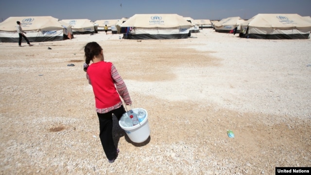 A Syrian girl carries a bucket filled with bottles of precious water to her family's tent in Jordan's al Za'atri refugee camp, September 04, 2012. (UNHCR)