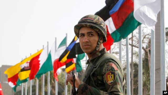 Seorang tentara pengawal presiden berjaga di depan bendera para peserta KTT Negara-negara Islam ke-12 yang berlangsung di Kairo, Mesir, 6 Februari 2013. (AP Photo/Amr Nabil). KTT akan berlangsung selama dua hari dengan pokok bahasan antara lain krisis di Suriah, Mali, kemiskinan dalam dunia Islam dan konflik di Afghanistan dan Somalia.